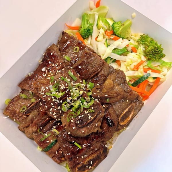 Ryuu Bowl's grilled short ribs with sesame seeds and green onions, served with steamed vegetables.