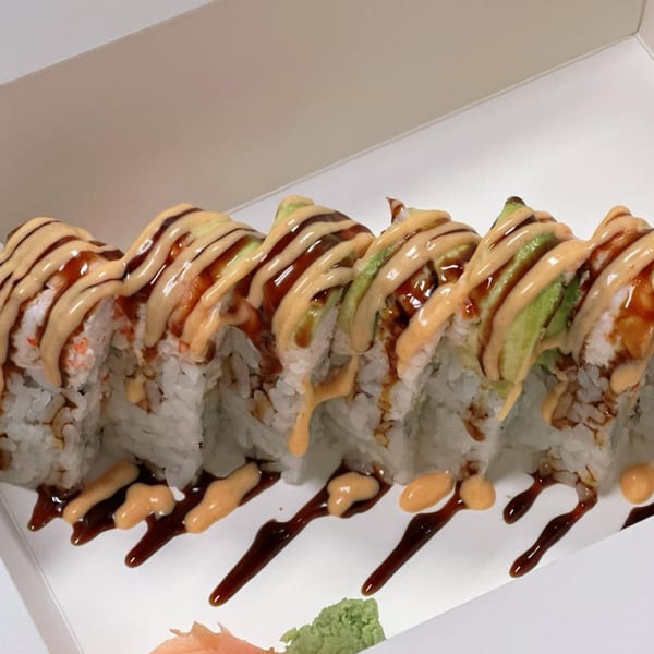 Ryuu Bowl sushi roll with avocado, drizzled with spicy mayo and eel sauce in a takeout box.