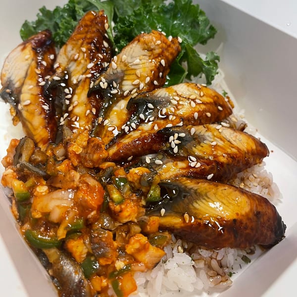 Ryuu Bowl's Japanese unagi bowl with glazed eel, sesame seeds, and green vegetables over rice.